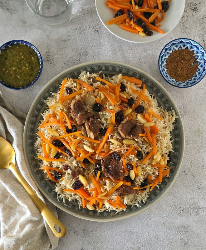 Afghan Pulao with tender meat and garnish with golden carrots, plump raisins, and toasted almonds and tomato chutney on the side