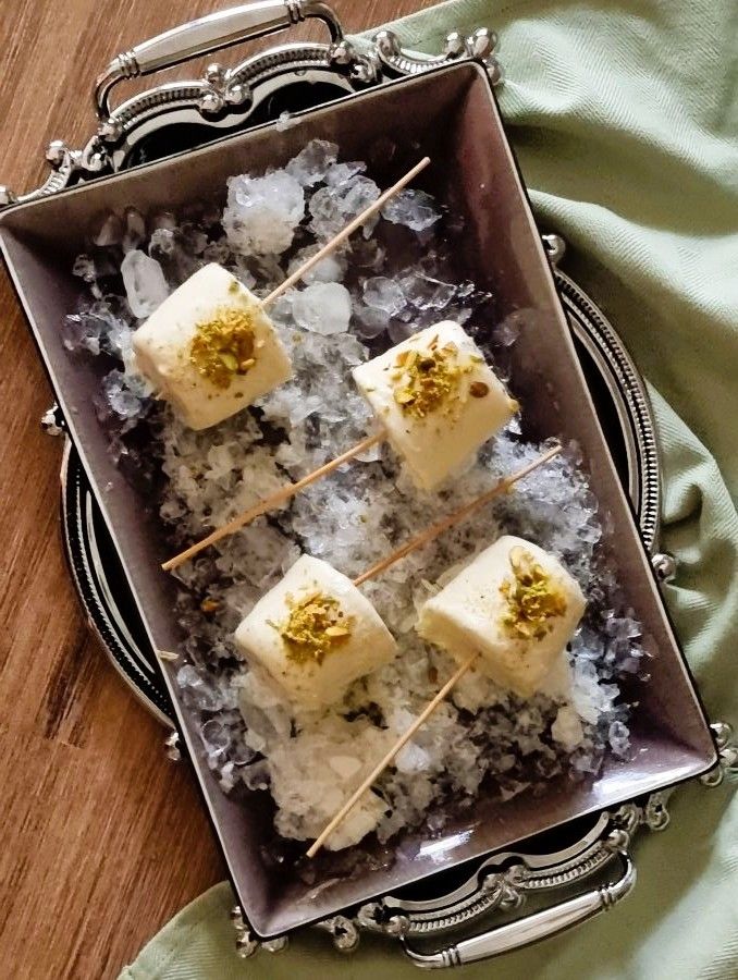 Refreshing pistachio kulfi on a stick resting over crushed ice