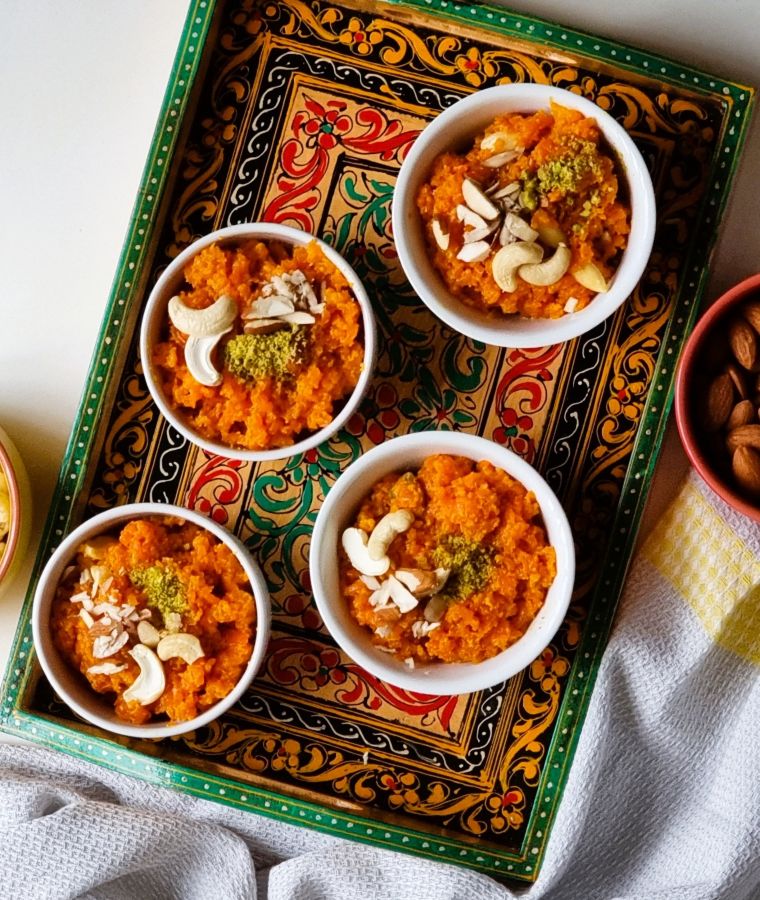 Close-up of carrot halwa (gajar halwa) garnished with chopped pistachios and cashews in a white bowl