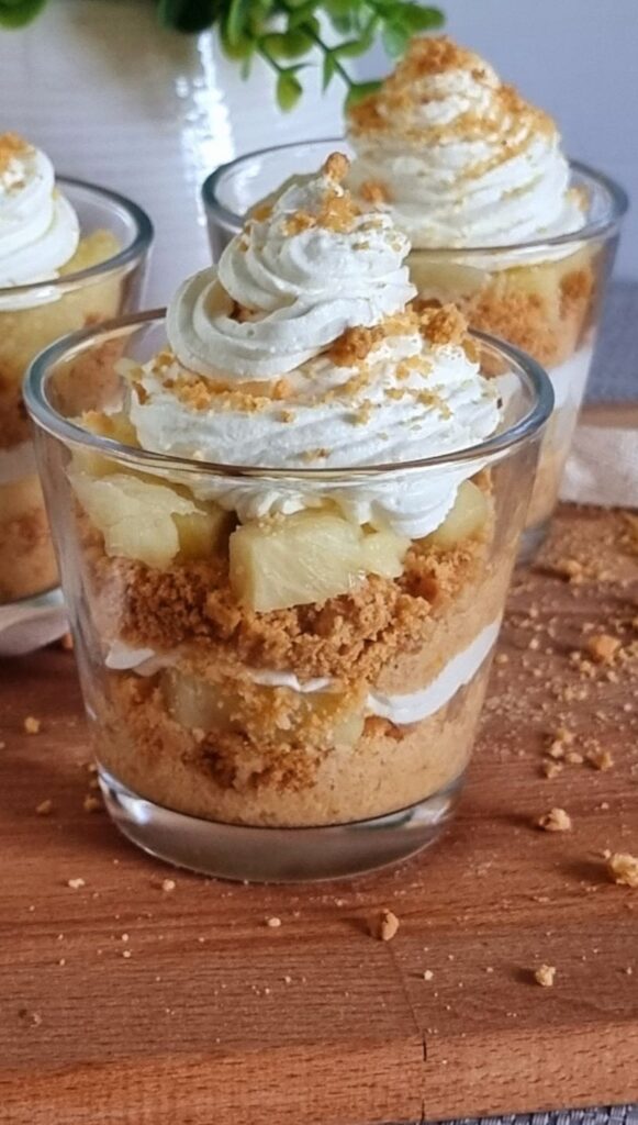 Close-up of Pineapple Delight in a glass with layers of biscuit crumbs, pineapple chunks, and whipped cream