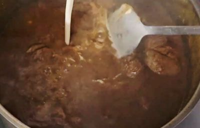 Pouring atta slurry into Beef Nihari to thicken the rich gravy