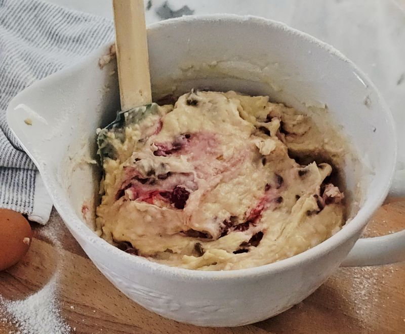 Folding fresh raspberries and chocolate chips gently into muffin batter
