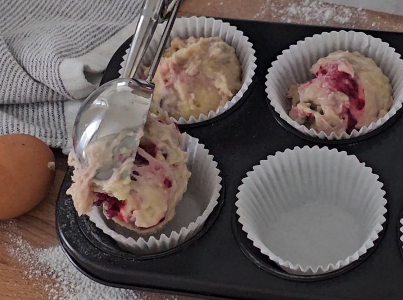 Muffin batter spooned into paper liners in a 12-cup muffin tray