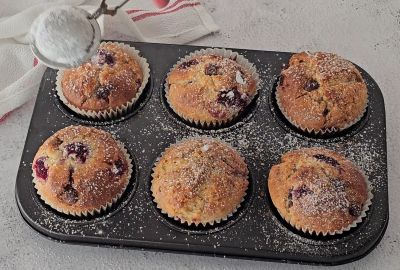 Icing sugar being dusted on raspberry chocolate chip muffin